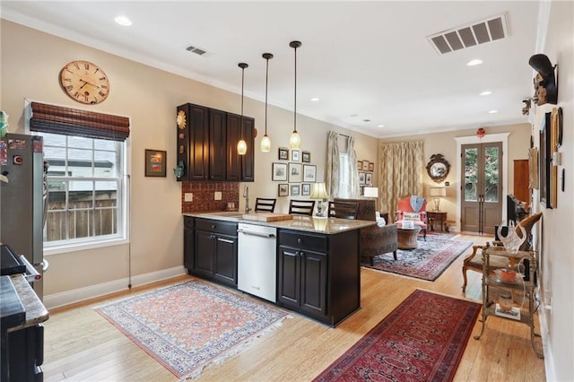 kitchen with pendant lighting, ornamental molding, stainless steel appliances, light stone counters, and light hardwood / wood-style floors