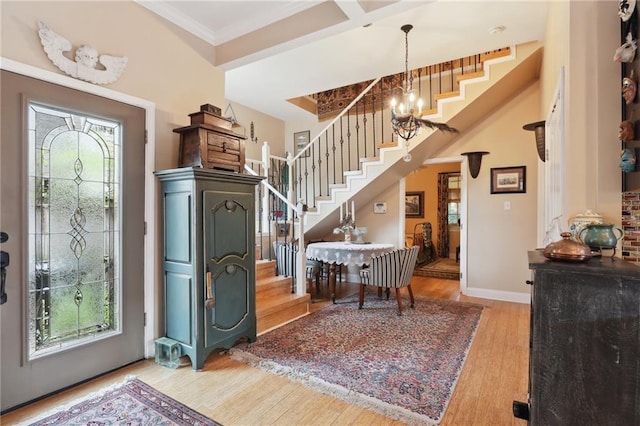 entryway with a wealth of natural light, coffered ceiling, a notable chandelier, and light hardwood / wood-style floors