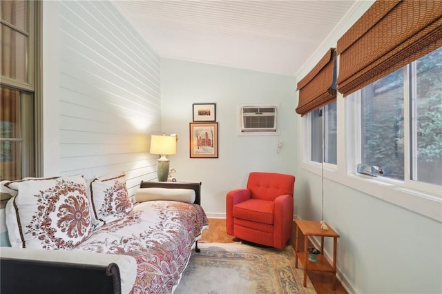 sitting room featuring lofted ceiling, plenty of natural light, hardwood / wood-style floors, and a wall mounted air conditioner