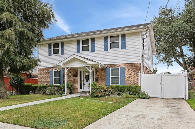 view of front of house featuring brick siding, a front lawn, fence, and a gate