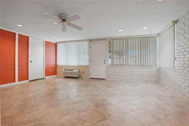 empty room with ceiling fan, brick wall, an AC wall unit, and recessed lighting