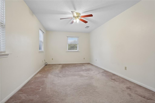 carpeted empty room with ceiling fan, visible vents, and baseboards