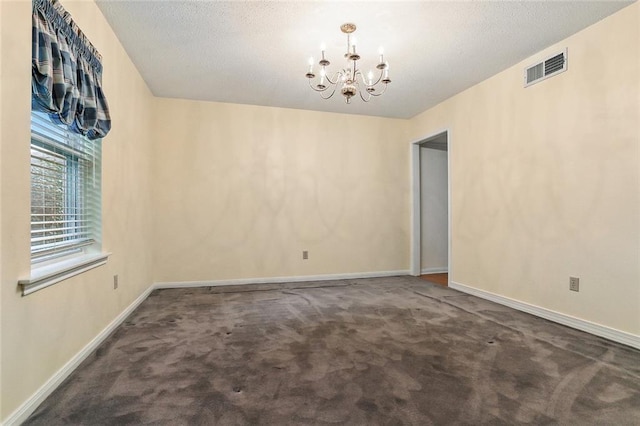 carpeted spare room with baseboards, visible vents, a chandelier, and a textured ceiling