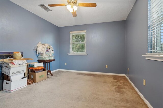 interior space with baseboards, visible vents, ceiling fan, and carpet flooring