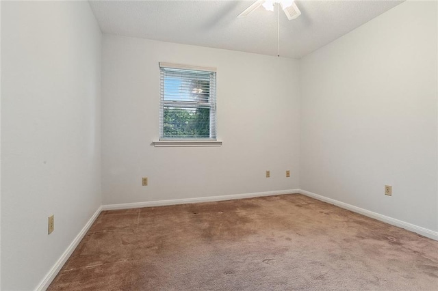 carpeted spare room featuring a ceiling fan and baseboards