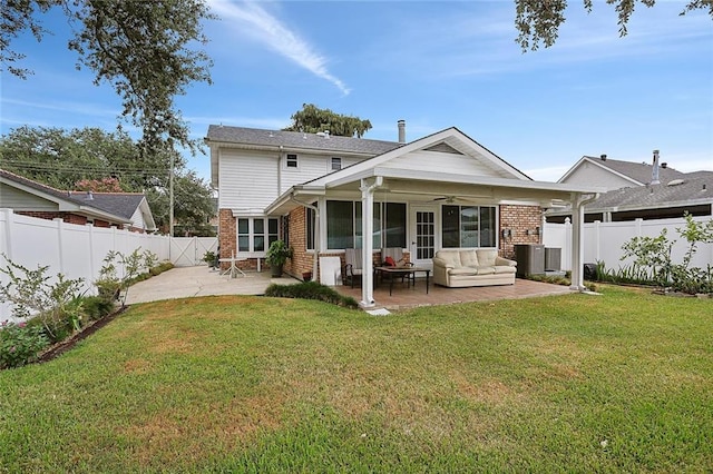 back of house with a yard, a patio, brick siding, and a fenced backyard