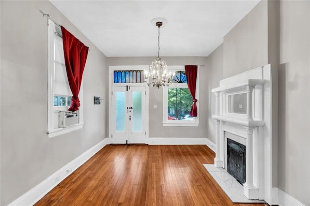 foyer with a chandelier, cooling unit, a fireplace with flush hearth, baseboards, and wood-type flooring