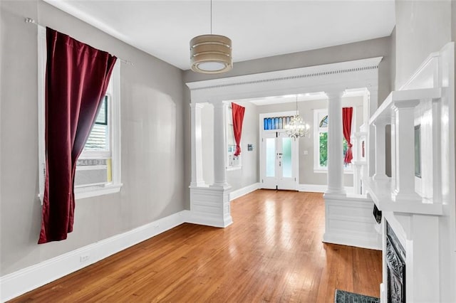 foyer entrance featuring decorative columns, baseboards, and hardwood / wood-style floors