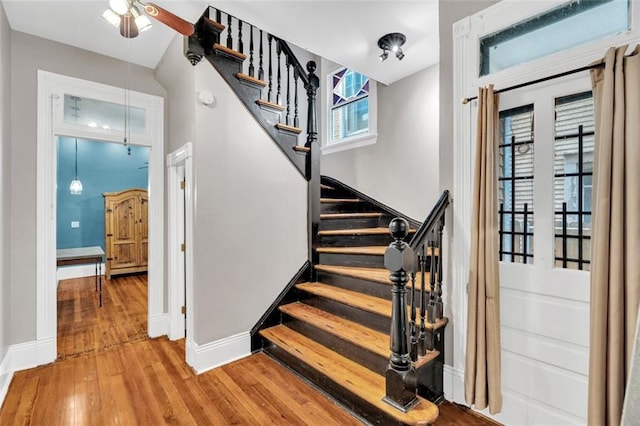 staircase featuring baseboards and wood finished floors