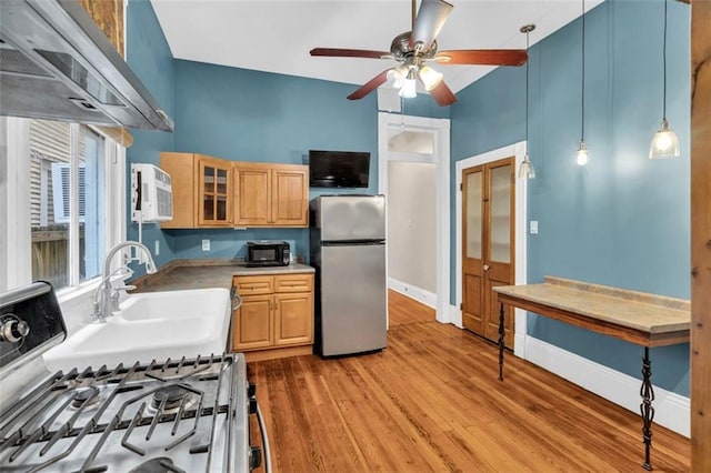 kitchen featuring light brown cabinets, light wood-type flooring, freestanding refrigerator, gas stove, and glass insert cabinets