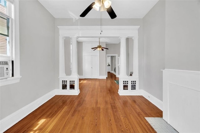 interior space featuring wood finished floors, decorative columns, and baseboards