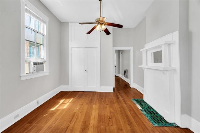 unfurnished bedroom with a closet, ceiling fan, wood finished floors, cooling unit, and baseboards