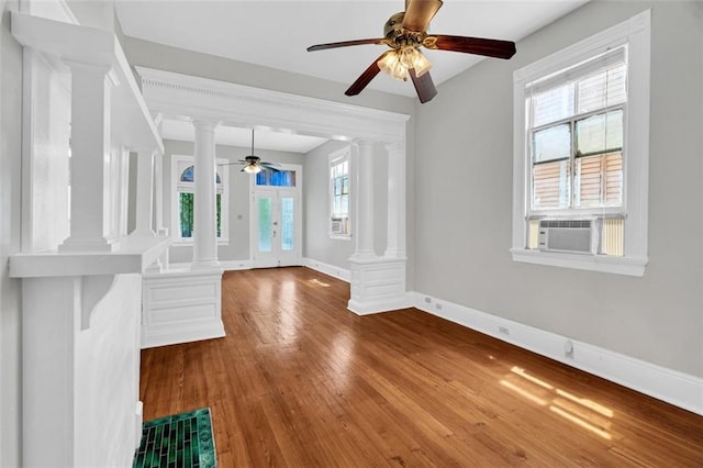 interior space featuring cooling unit, wood-type flooring, decorative columns, and baseboards