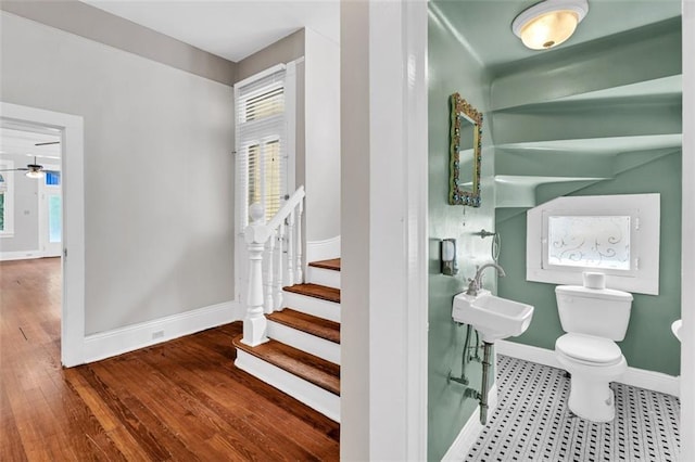 stairs featuring a healthy amount of sunlight, ceiling fan, baseboards, and wood finished floors