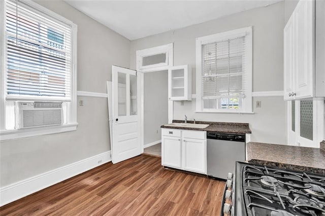 kitchen with white cabinets, dark countertops, appliances with stainless steel finishes, wood finished floors, and a sink