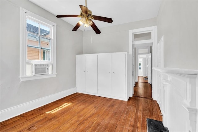 unfurnished bedroom with a closet, baseboards, a ceiling fan, cooling unit, and hardwood / wood-style floors