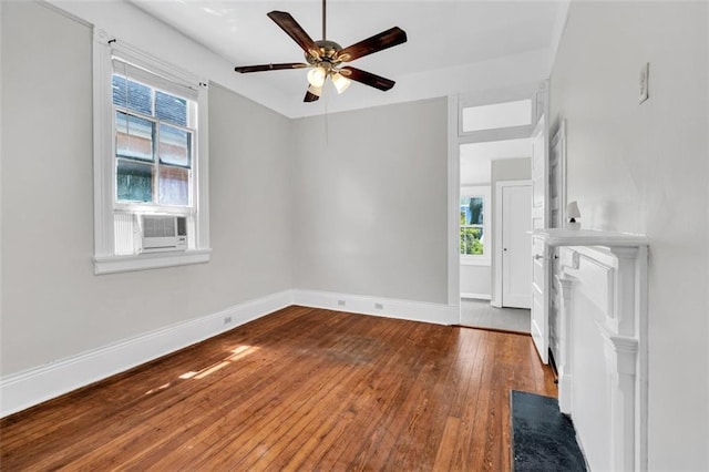 unfurnished living room featuring plenty of natural light, ceiling fan, wood-type flooring, and baseboards