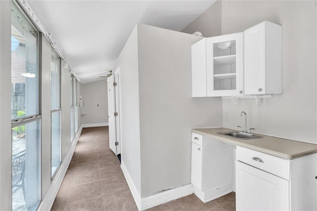 kitchen featuring glass insert cabinets, white cabinetry, a sink, and light tile patterned floors