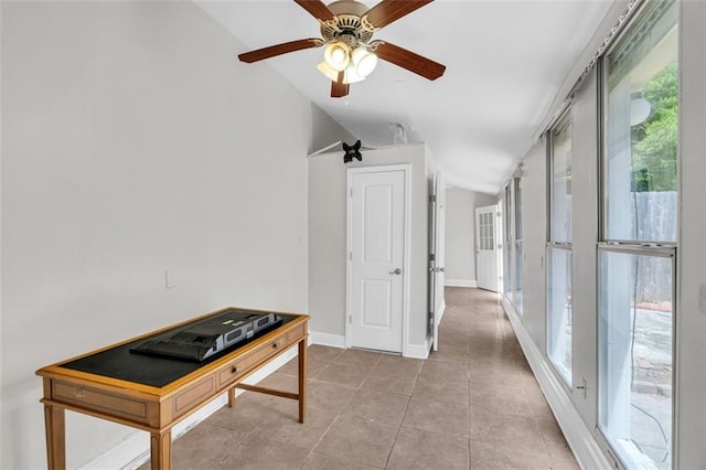 corridor featuring tile patterned flooring, baseboards, and vaulted ceiling