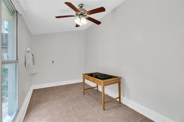 tiled empty room featuring a ceiling fan, vaulted ceiling, and baseboards