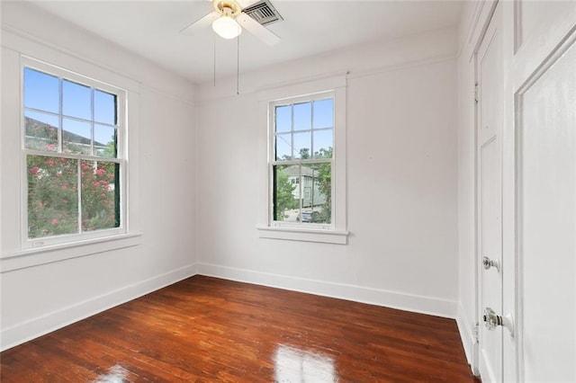 empty room with dark wood-type flooring, ceiling fan, and a wealth of natural light