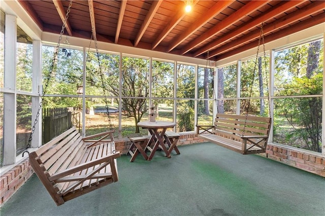 unfurnished sunroom featuring beamed ceiling, a healthy amount of sunlight, and wood ceiling