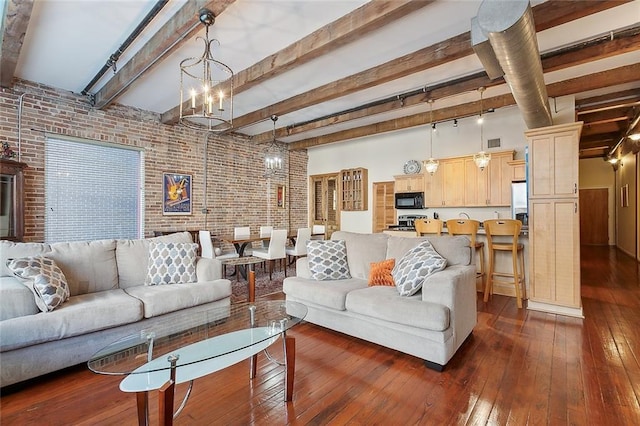 living room featuring brick wall, beam ceiling, a chandelier, and dark hardwood / wood-style flooring