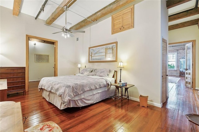 bedroom with ceiling fan, dark hardwood / wood-style flooring, and beam ceiling