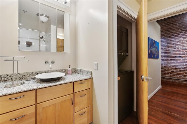 bathroom featuring wood-type flooring, brick wall, and vanity