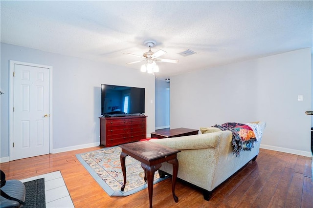 living room with baseboards, visible vents, and hardwood / wood-style floors