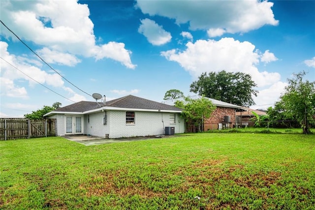 back of property with french doors, a fenced backyard, a lawn, and central AC unit