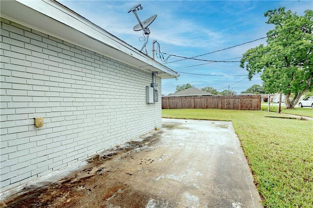 view of side of property with a lawn, a patio area, and fence