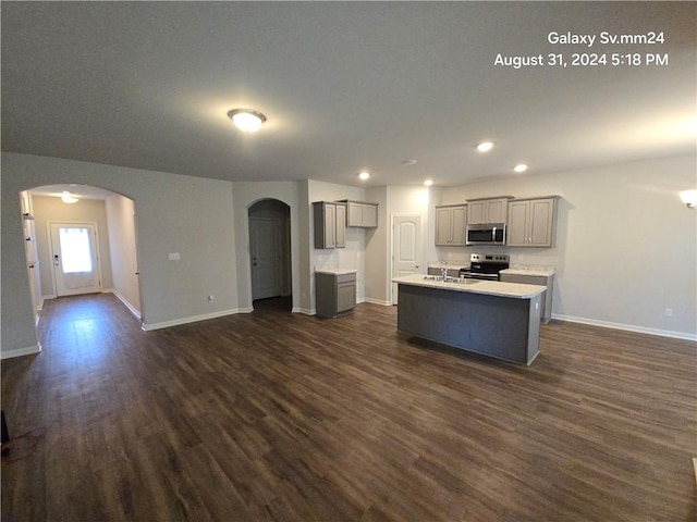 kitchen featuring appliances with stainless steel finishes, sink, gray cabinets, dark wood-type flooring, and a center island with sink