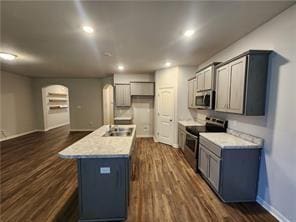 kitchen featuring a kitchen island with sink, dark hardwood / wood-style flooring, stainless steel appliances, and sink