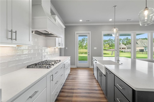 kitchen featuring decorative light fixtures, white cabinets, stainless steel appliances, and an island with sink