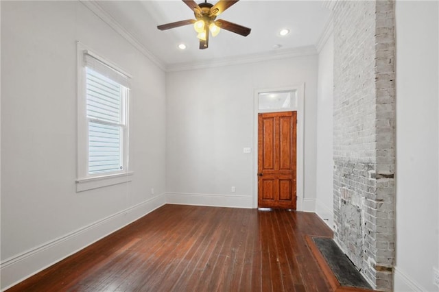 unfurnished room featuring a large fireplace, ceiling fan, ornamental molding, and wood-type flooring