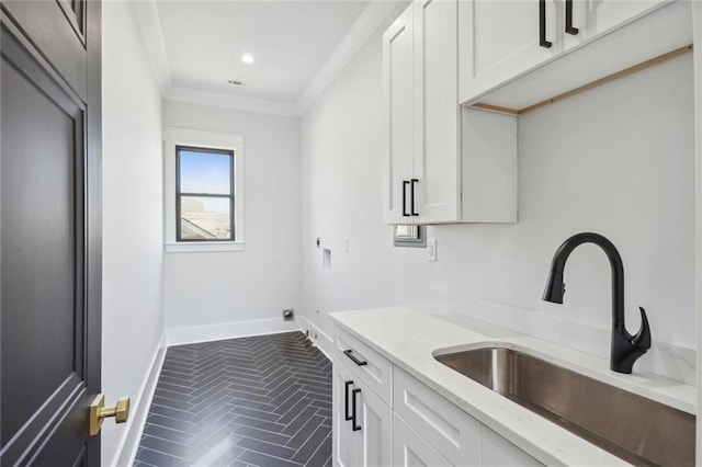 kitchen with crown molding, light stone counters, and white cabinetry