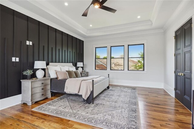 bedroom featuring a tray ceiling, ceiling fan, and wood-type flooring