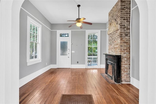 entryway with hardwood / wood-style floors, plenty of natural light, a fireplace, and ceiling fan