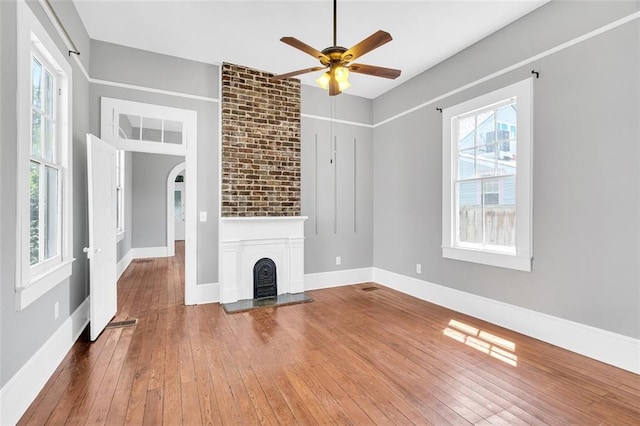 unfurnished living room featuring a large fireplace, ceiling fan, and wood-type flooring