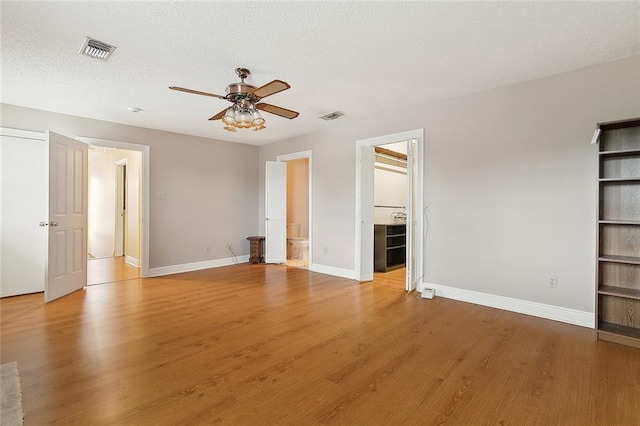 unfurnished bedroom featuring visible vents, a textured ceiling, baseboards, and wood finished floors