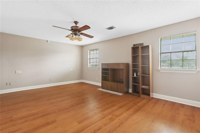 unfurnished living room featuring light wood-style floors, a textured ceiling, baseboards, and a ceiling fan