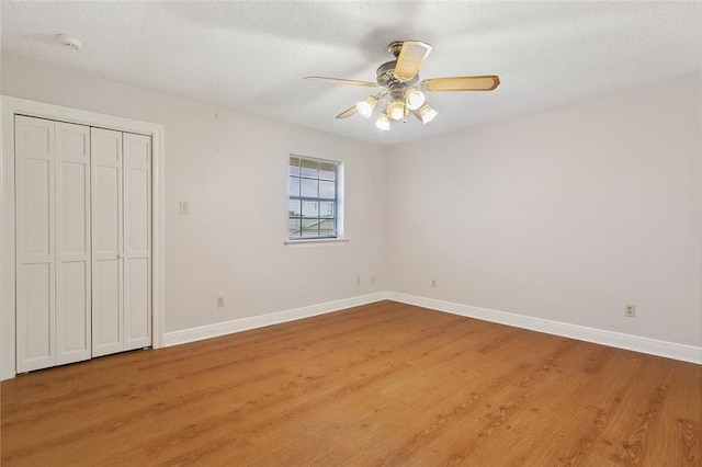 unfurnished bedroom with light wood-style floors, a closet, ceiling fan, and baseboards