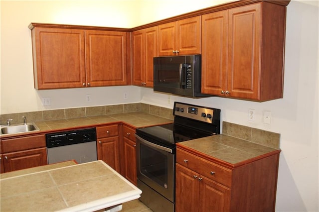 kitchen with tile counters, sink, and appliances with stainless steel finishes