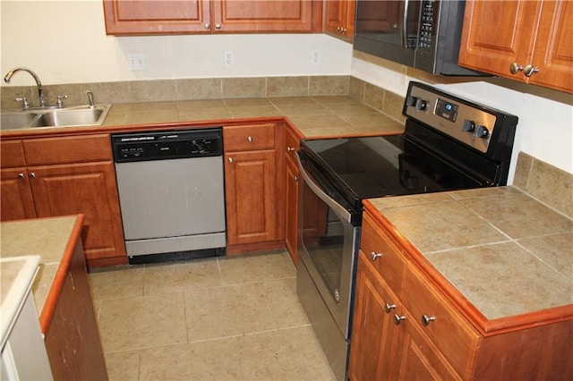 kitchen featuring light tile patterned floors, dishwashing machine, stainless steel electric stove, sink, and tile counters