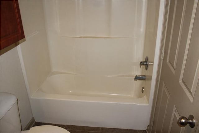 bathroom featuring toilet, washtub / shower combination, and tile patterned flooring