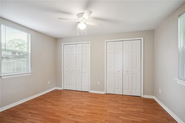 unfurnished bedroom featuring light hardwood / wood-style flooring, two closets, and ceiling fan