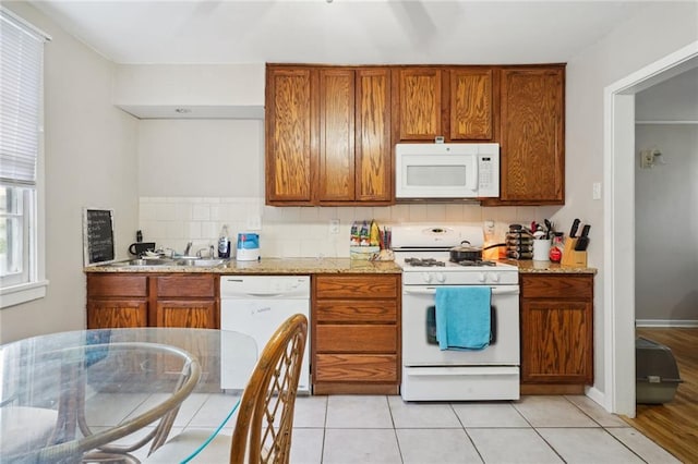 kitchen with light stone countertops, white appliances, sink, and light hardwood / wood-style flooring