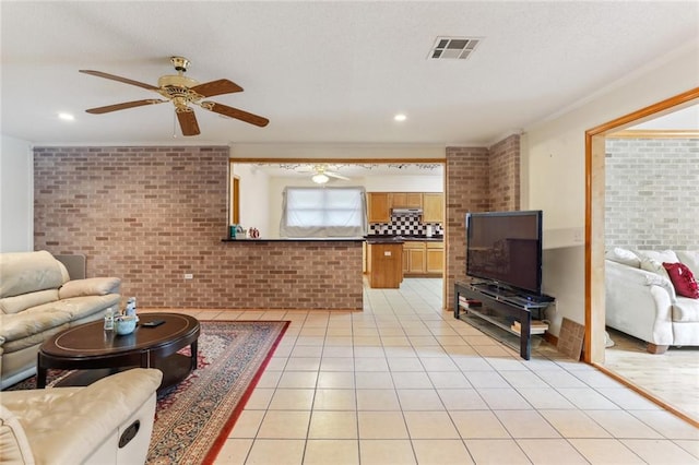 living room featuring ceiling fan, light tile patterned floors, ornamental molding, and brick wall