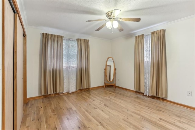 spare room featuring light wood-type flooring, ornamental molding, ceiling fan, and a textured ceiling